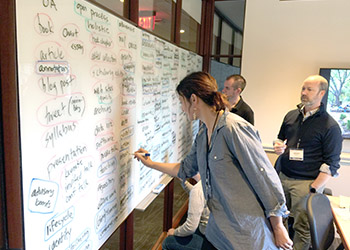Faculty members working on a board